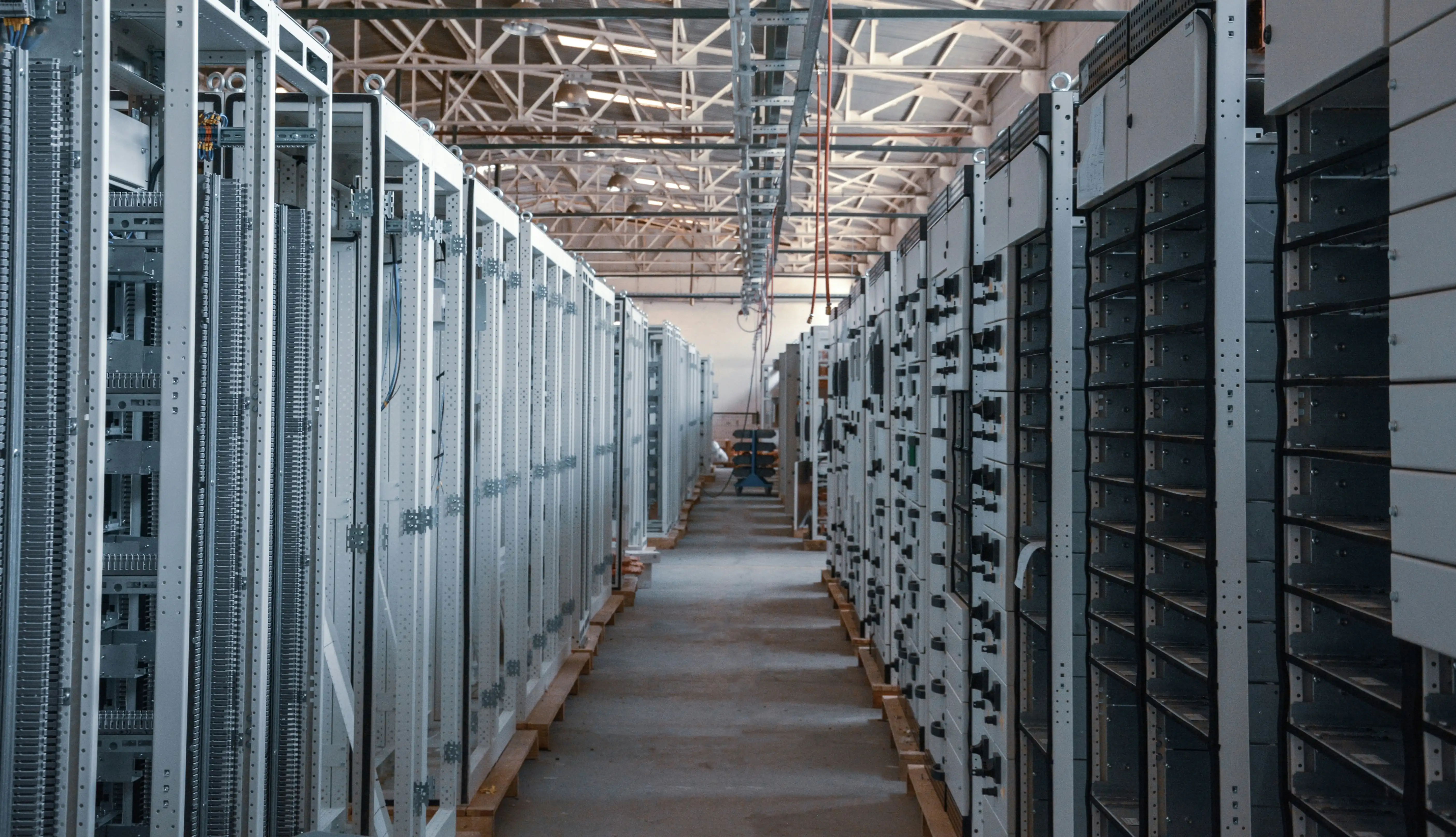 A long, brightly lit data center aisle lined with rows of server cabinets.