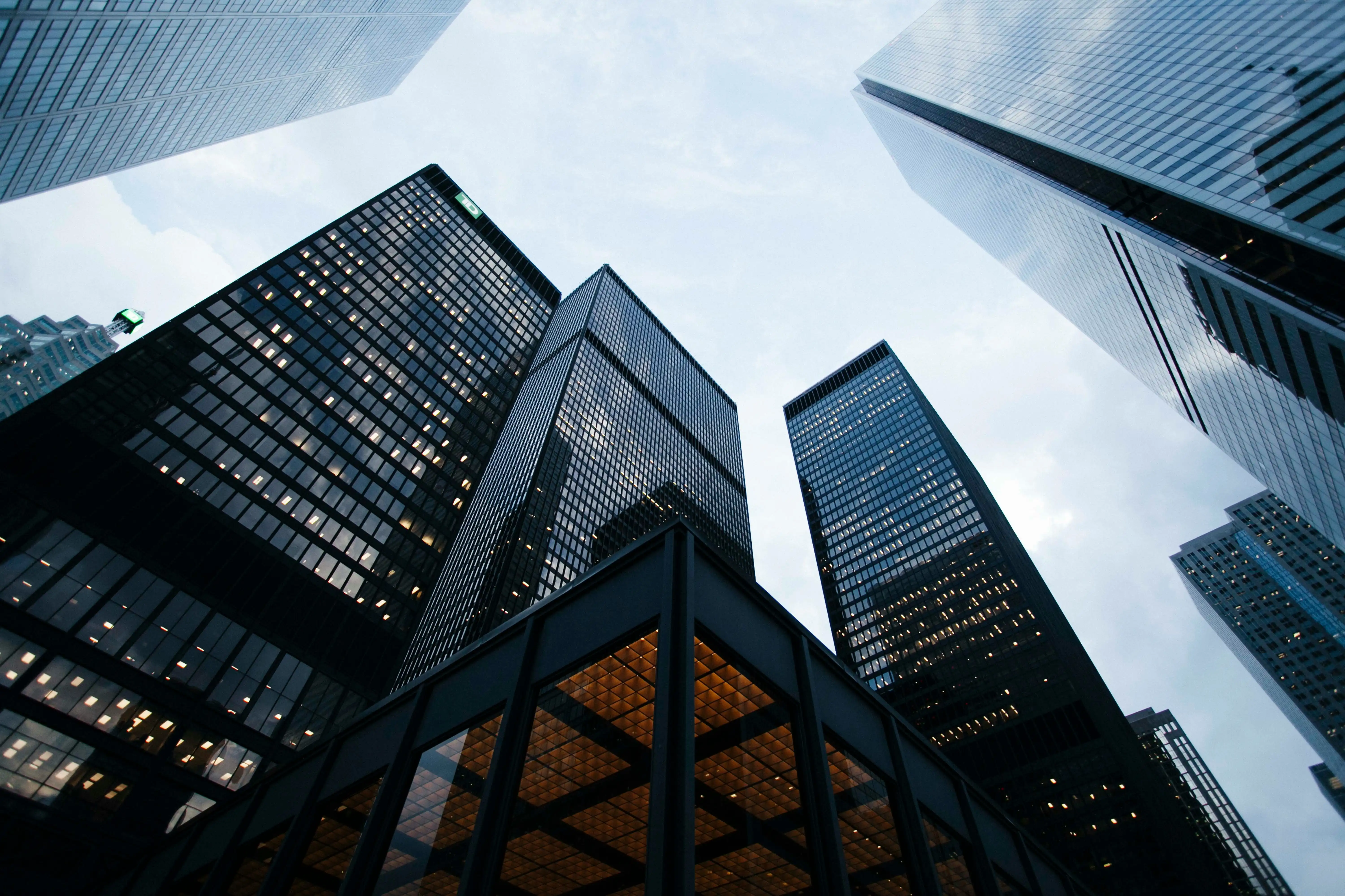 Glass financial-district office towers seen looking upward against the sky.