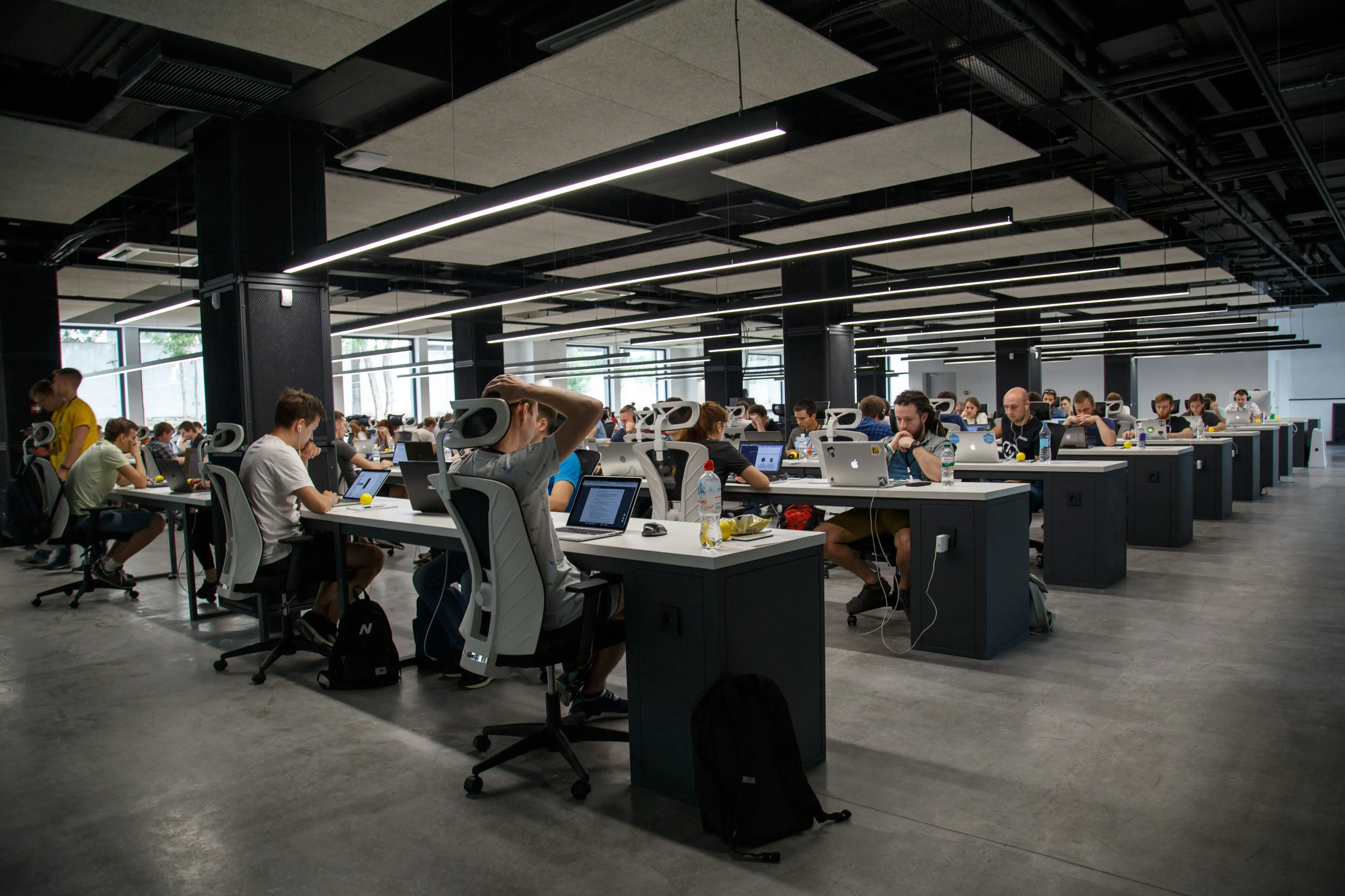A large open-plan tech office with rows of people working at laptops.